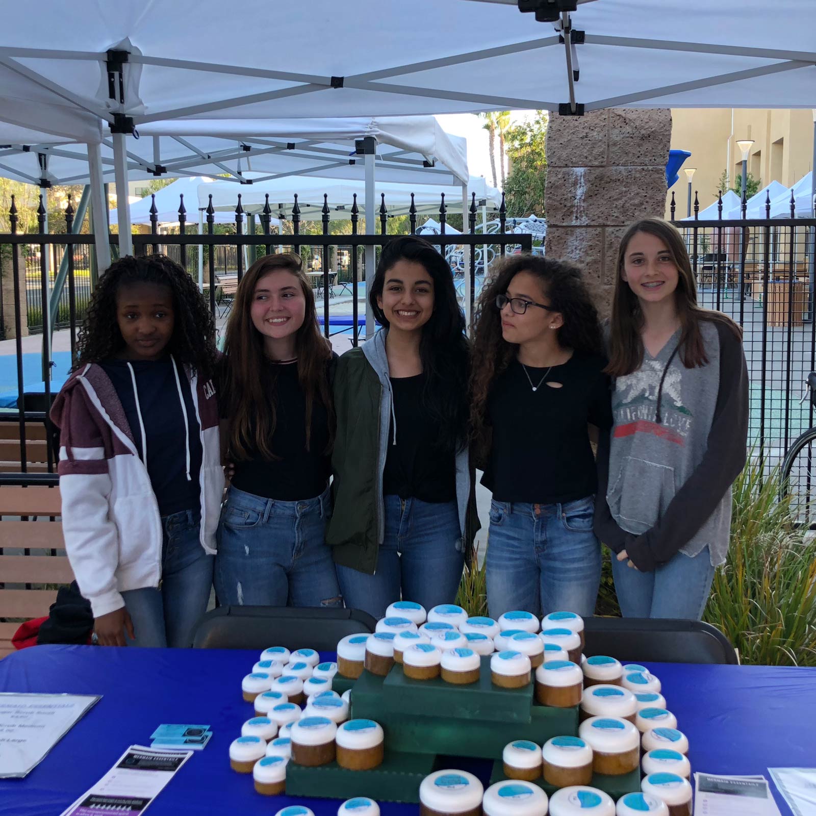 A group of middle school students stand behind a display table.